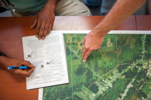 Hands pointing to locations on a printed map during GIS fieldwork.