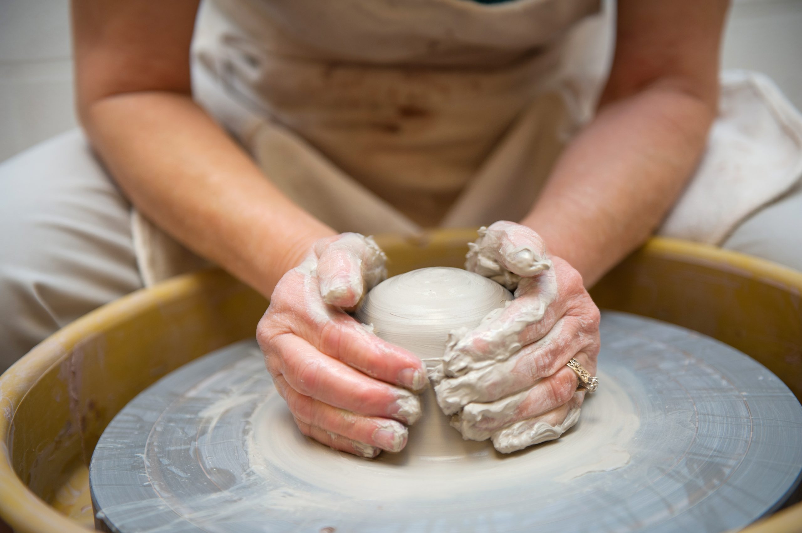 A person using a potter's wheel to create something with clay.