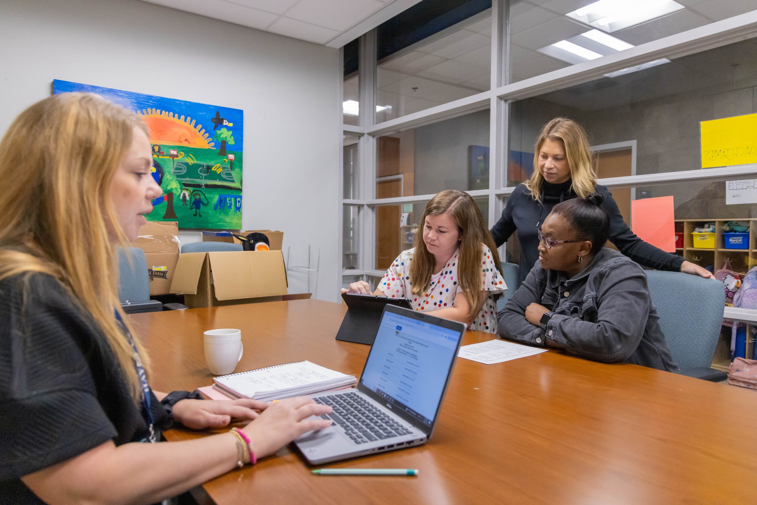 School administrators sitting around a conference table in a meeting, with a laptop and other materials on the table.