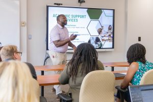 Delta State University staff member giving a presentation on Academic Support Services to a small group.