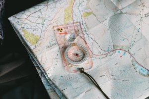 Compass resting on topographic map used for geospatial navigation.