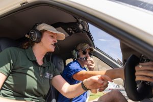 Instructor pointing out flight controls to a student during hands-on cockpit training.