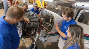 Aviation students examining an aircraft engine during a hands-on maintenance lesson.
