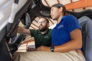 Instructor and student reviewing aircraft instruments inside a cockpit.