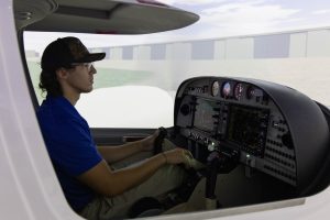 DSU student operating a flight simulator in an aviation training lab.