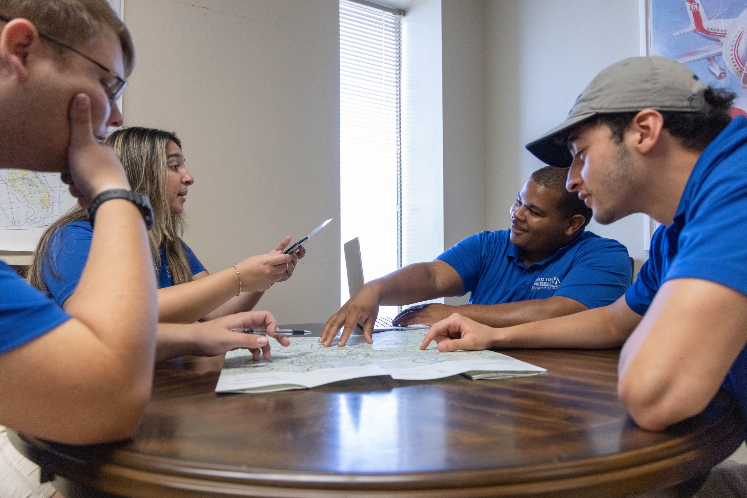 A group of aviation students sitting around a table discussing flight materials.