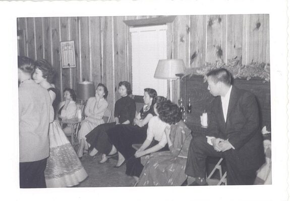 Young adults sitting next to each other at social event, B&W.