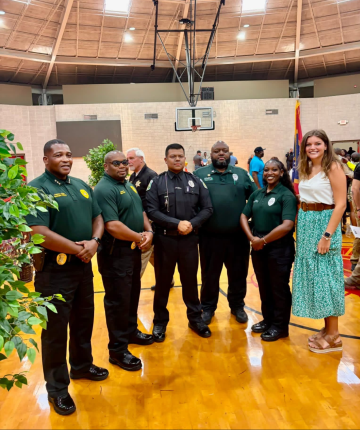 From left to right, Deputy Chief Christopher Williams, Lieutenant William Taylor, Officer Marcelo Rojas, Sergeant Jonathan Johnson, Officer Mykalia Harris and DSU Public Safety Coordinator Hannah-Linn Holcomb standing in a gym following graduation.
