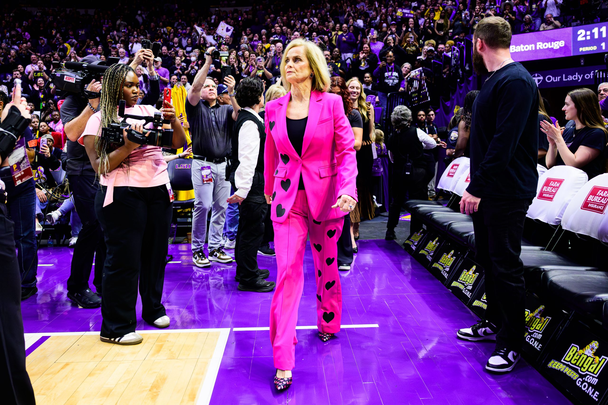 a woman in a pink suit walking onto a basketball court.