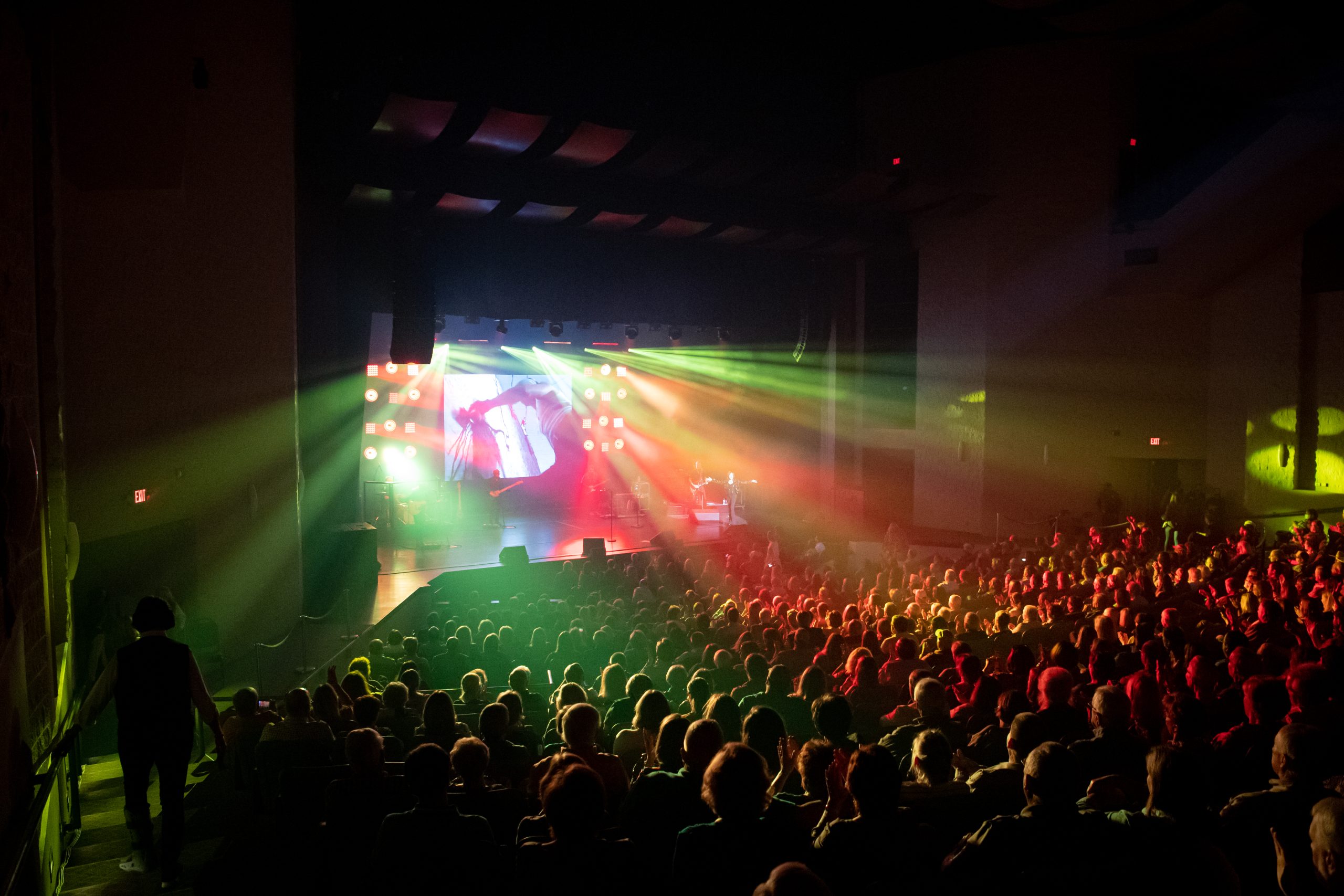 a full auditorium with colored lights beaming from the stage