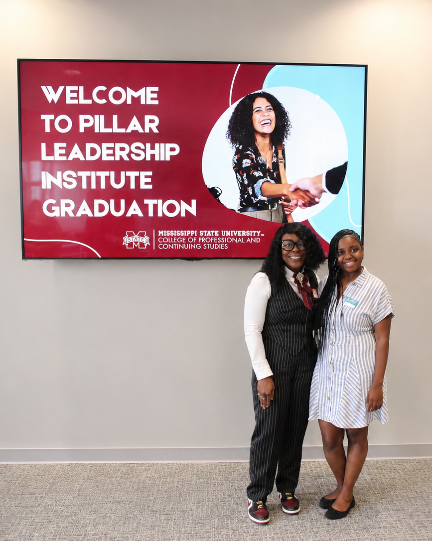 2 women standing below a sign for the Pillar Leadership Institute