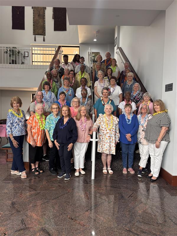 a large group of volunteers posing on a staircase inside a performing arts center's lobby.