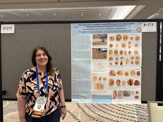 a biology professor standing by a research poster