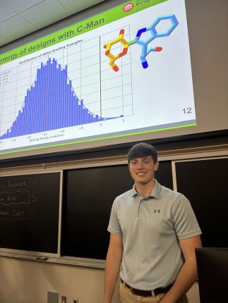 a student standing in front of a research presentation.