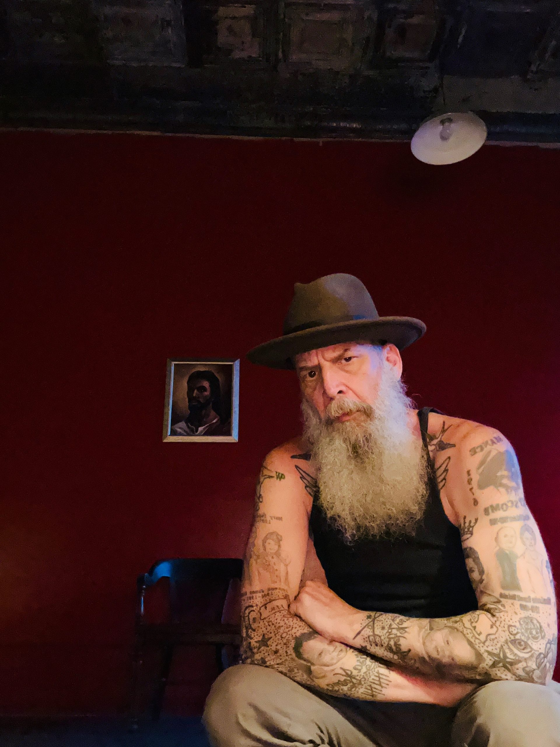 an artist with a long grey beard and tattoos