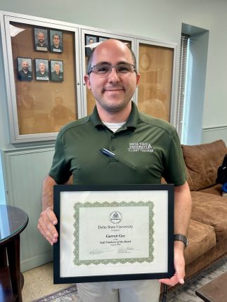 a man in a green shirt holding a certificate