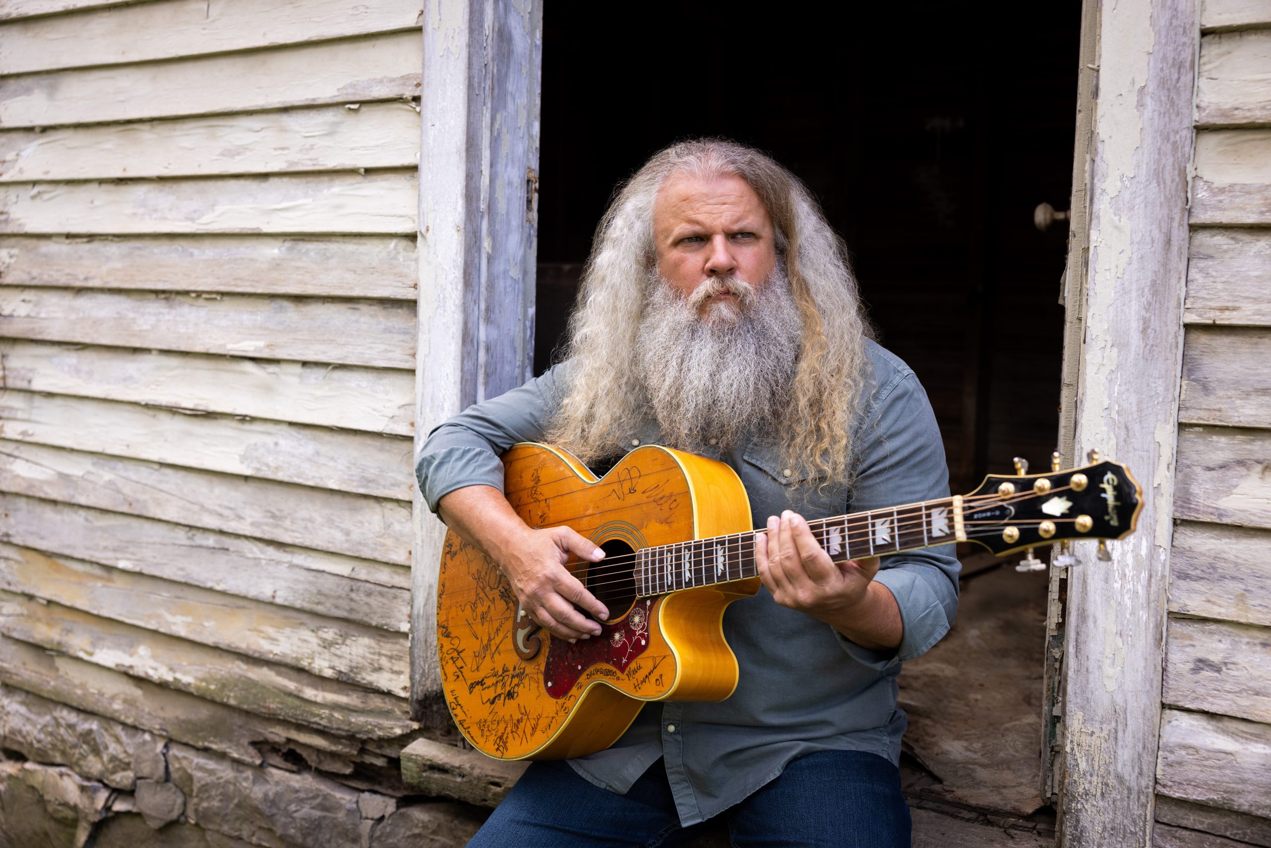 a man with long white hair and long white beard with a guitar