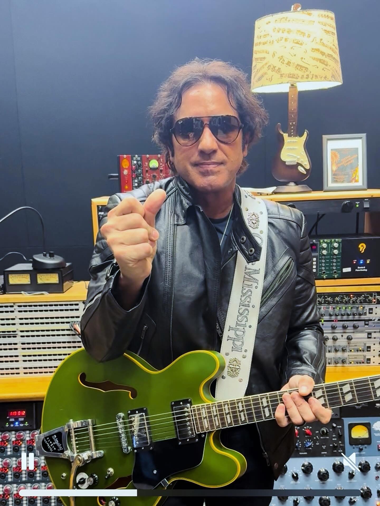 a man in a recording studio holding a green guitar