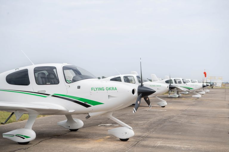 white single engine airplanes lined up on a taxiway
