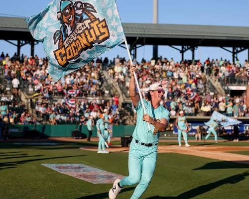 a baseball player running onto the field carrying a large Loco Beach Coconuts flag