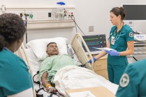 Students working through a patient care simulation using a medical mannequin.