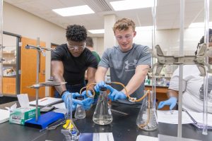 Students working together on a chemistry experiment using laboratory glassware and equipment.