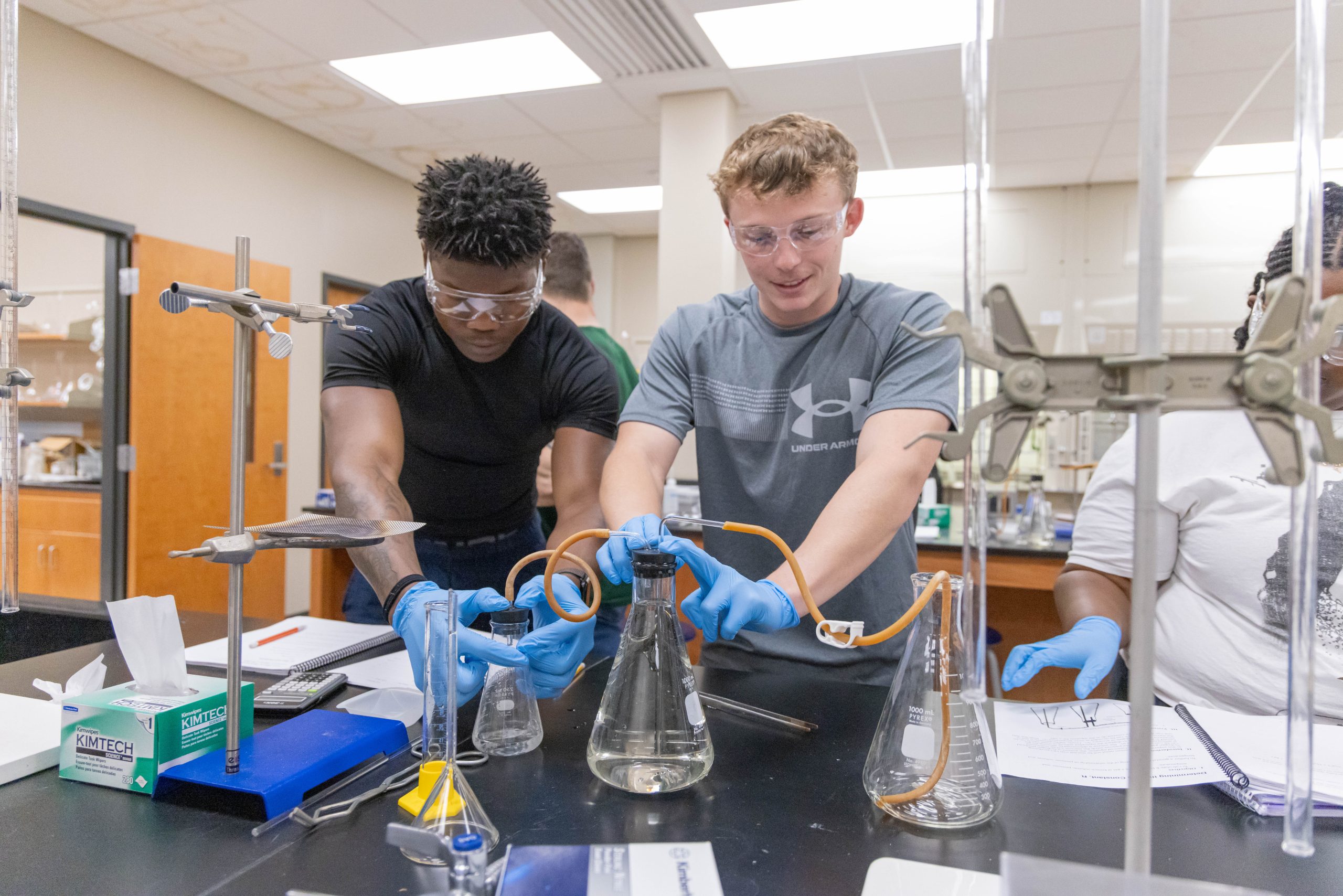 Students working together on a chemistry experiment using laboratory glassware and equipment.