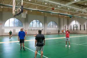 Students playing basketball on an indoor recreation court.