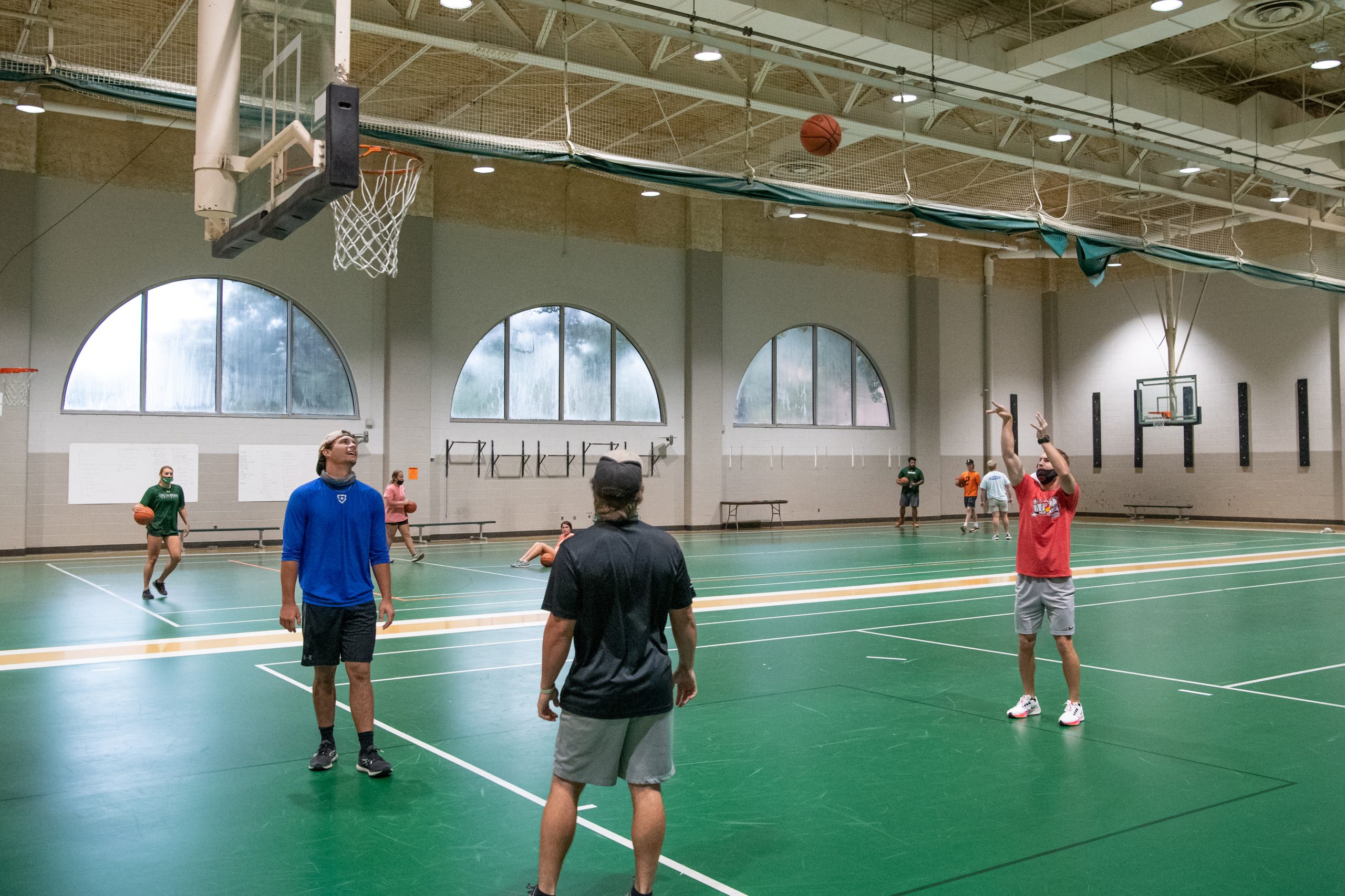 Students playing basketball on an indoor recreation court.