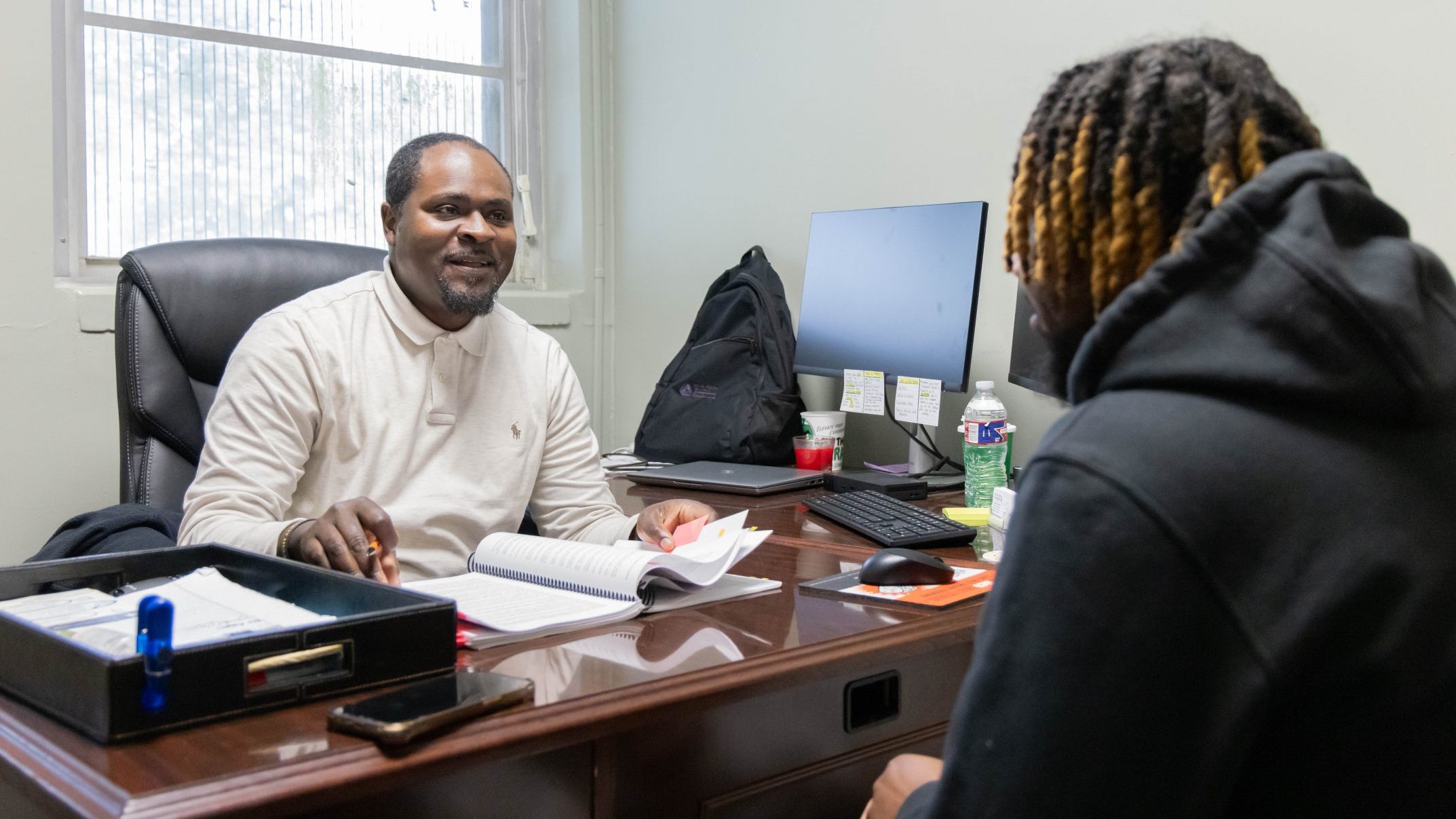 Advisor smiling while speaking with a student during a one-on-one meeting in an office setting.