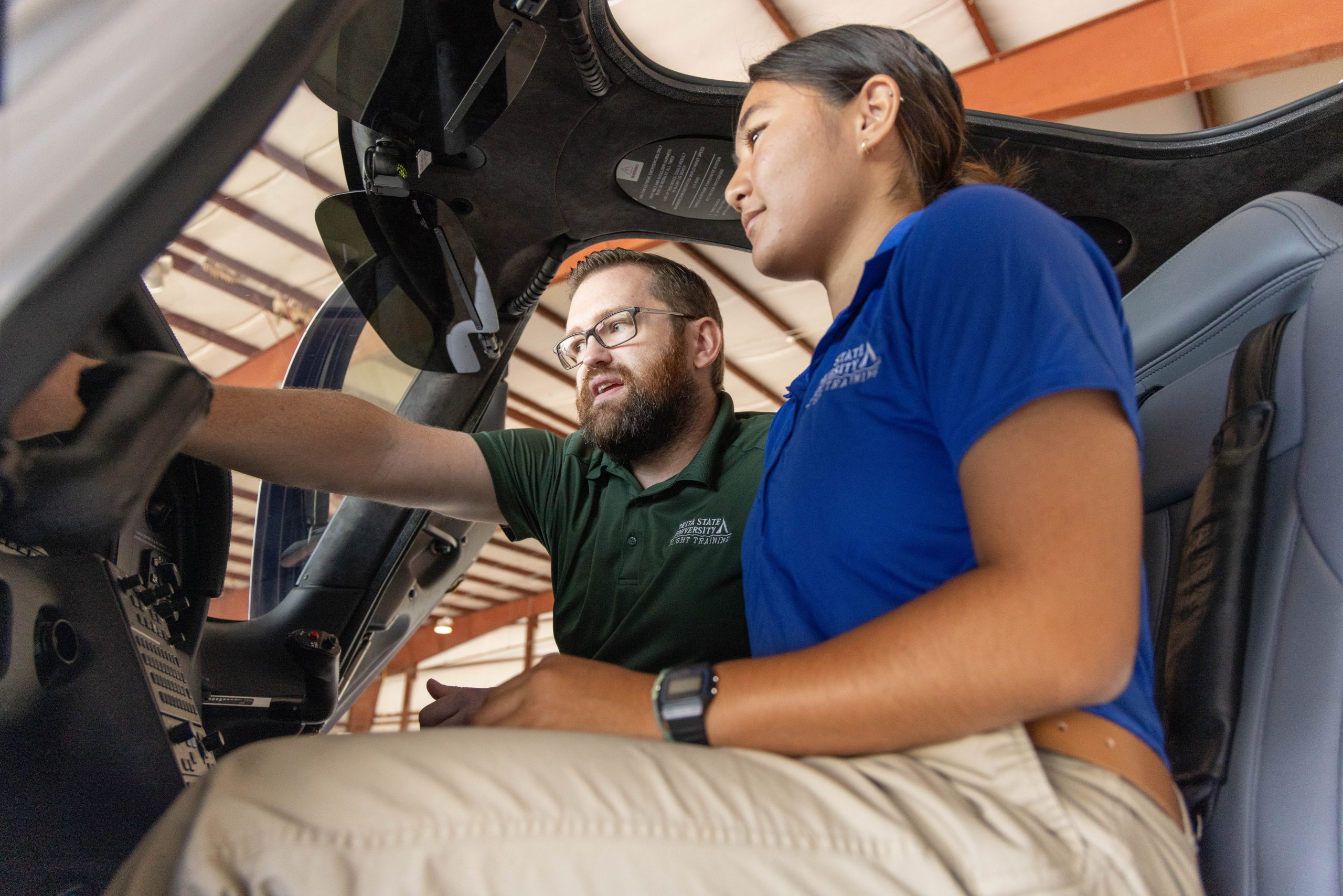 Instructor and student reviewing aircraft instruments inside a cockpit.